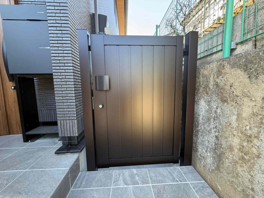 玄関ポーチから建物裏へ続くYKK APのシンプレオ門扉